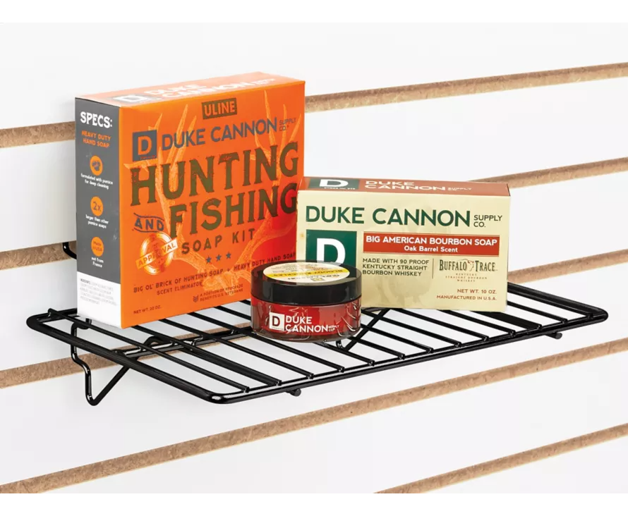 The versatile black wire shelf securely holding merchandise and installed on a standard white slatwall panel.