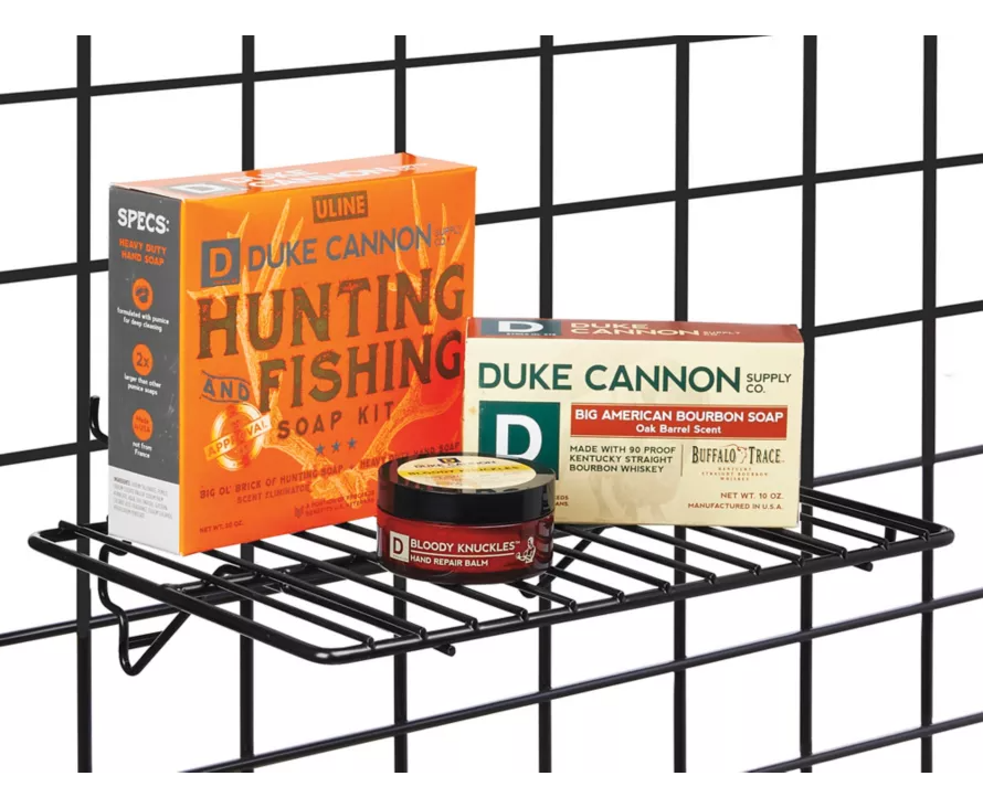 Installing the black metal wire shelf on a perforated pegboard, ideal for hardware stores or creative home organization.