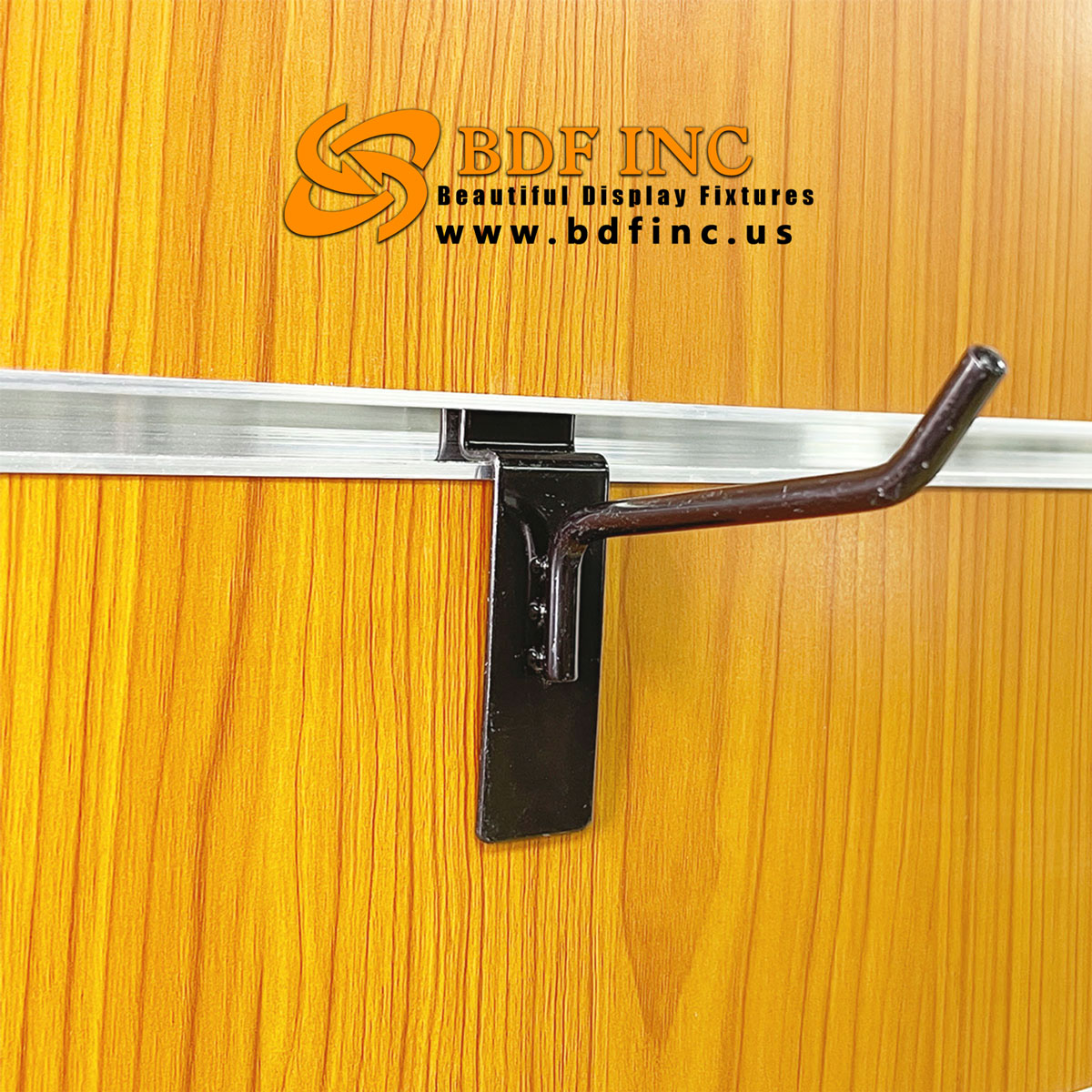 Black metal slatwall hook installed on slatwall display panel holding retail items