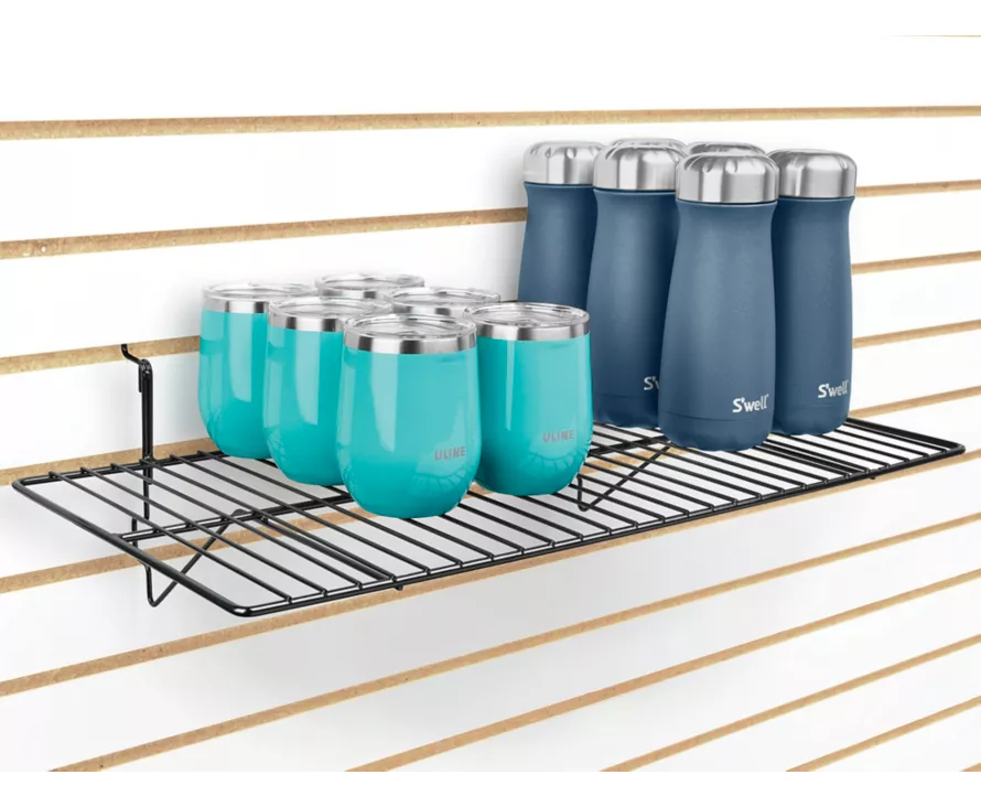 The large 12x24 inch black wire shelf installed on slatwall, providing ample space for multiple pairs of shoes or bulky retail products.