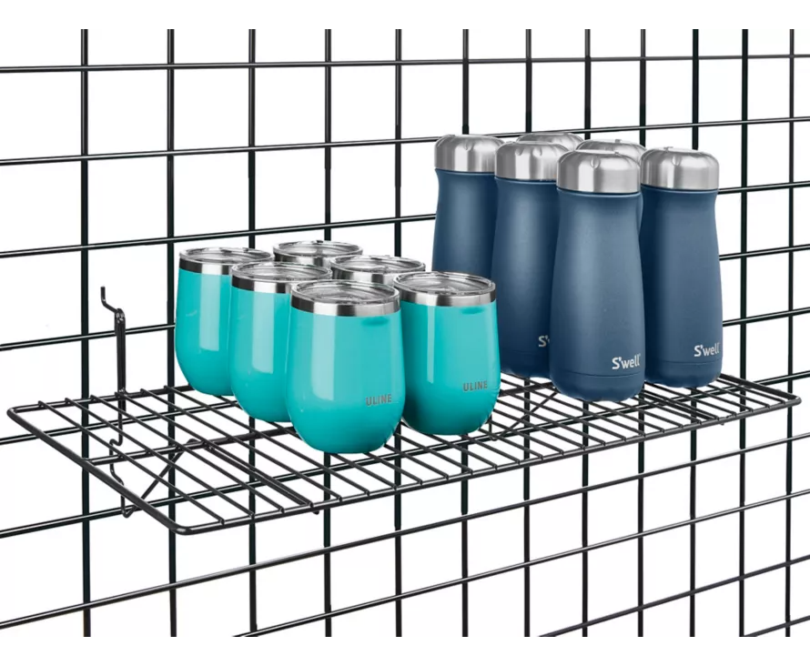 Spacious 12x24 inch black shelf securely installed on wire gridwall, creating a versatile display for bags and apparel.